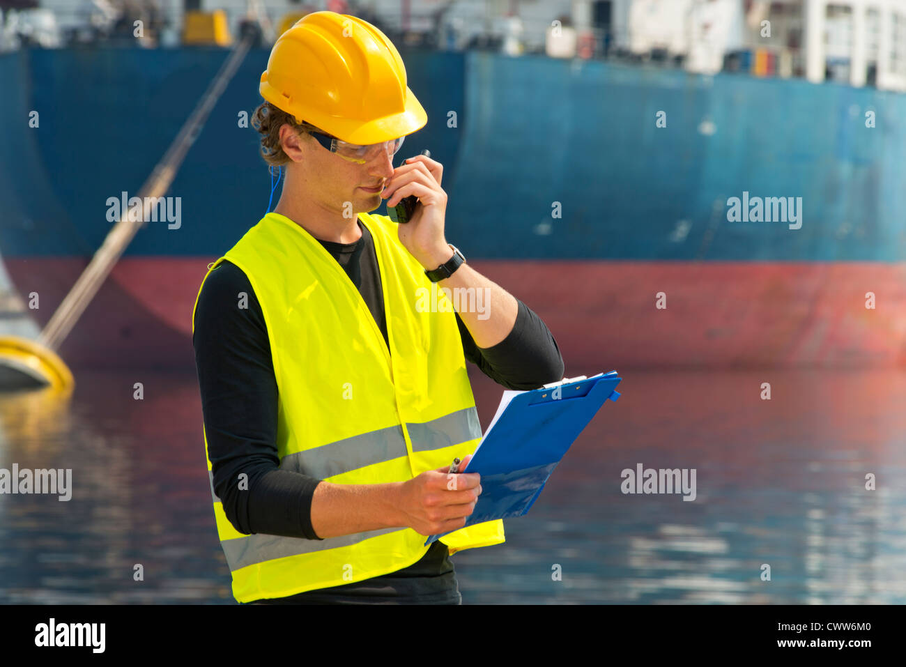 Engineer, reading out instructions from the notes on his clipboard over the radio Stock Photo