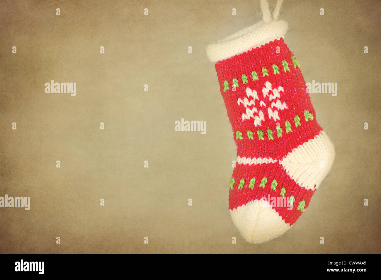 Cute knitted Christmas sock / stocking hanging on rustic vintage textured background Stock Photo