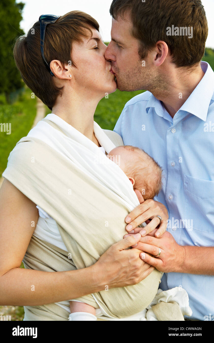 Couple kissing with infant outdoors Stock Photo