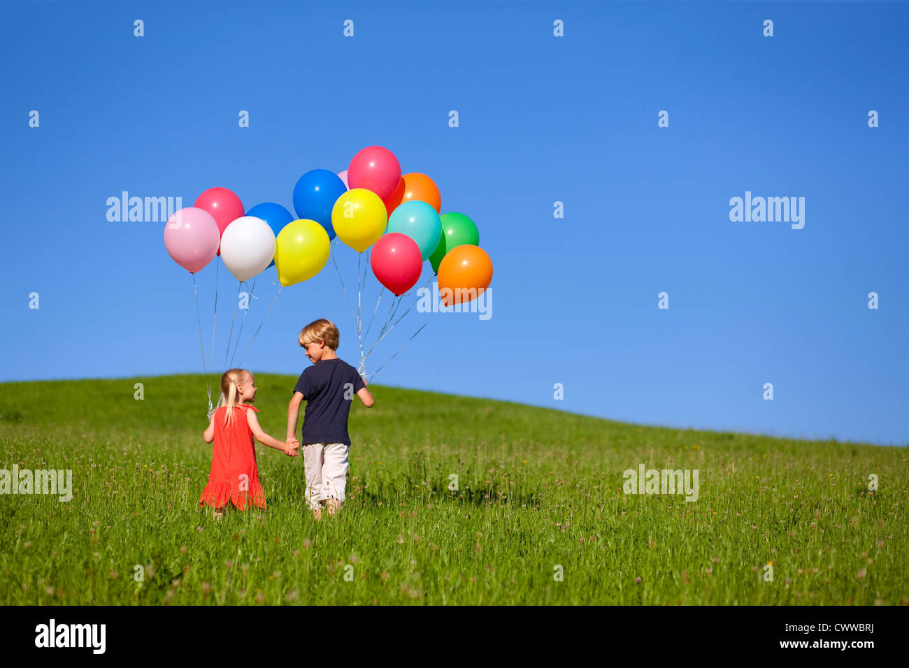 Children with colorful balloons in grass Stock Photo