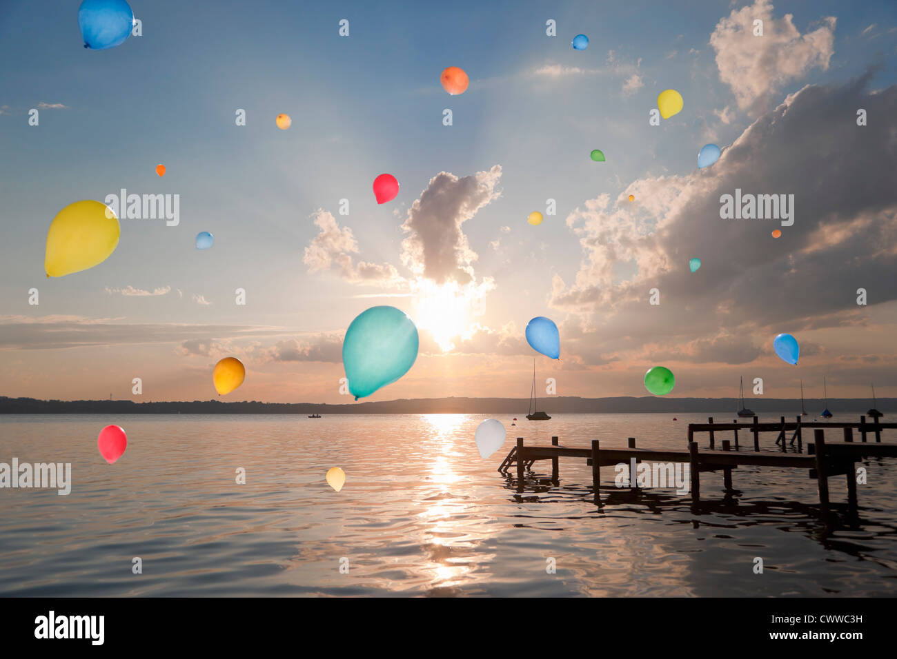 Balloons floating over still lake Stock Photo
