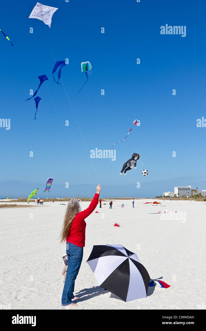 Woman flying kite with a Dali style clock face on beach at the Treasure Island Kite Festival in Treasure Island, Florida Stock Photo