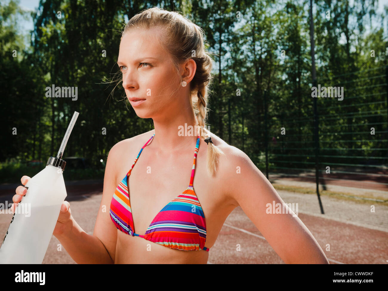 Woman drinking water on tennis court Stock Photo