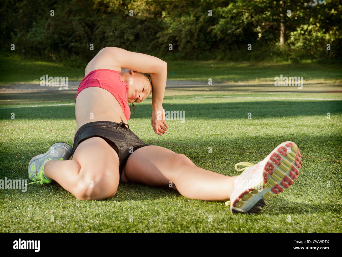 Runner stretching on grass in park Stock Photo