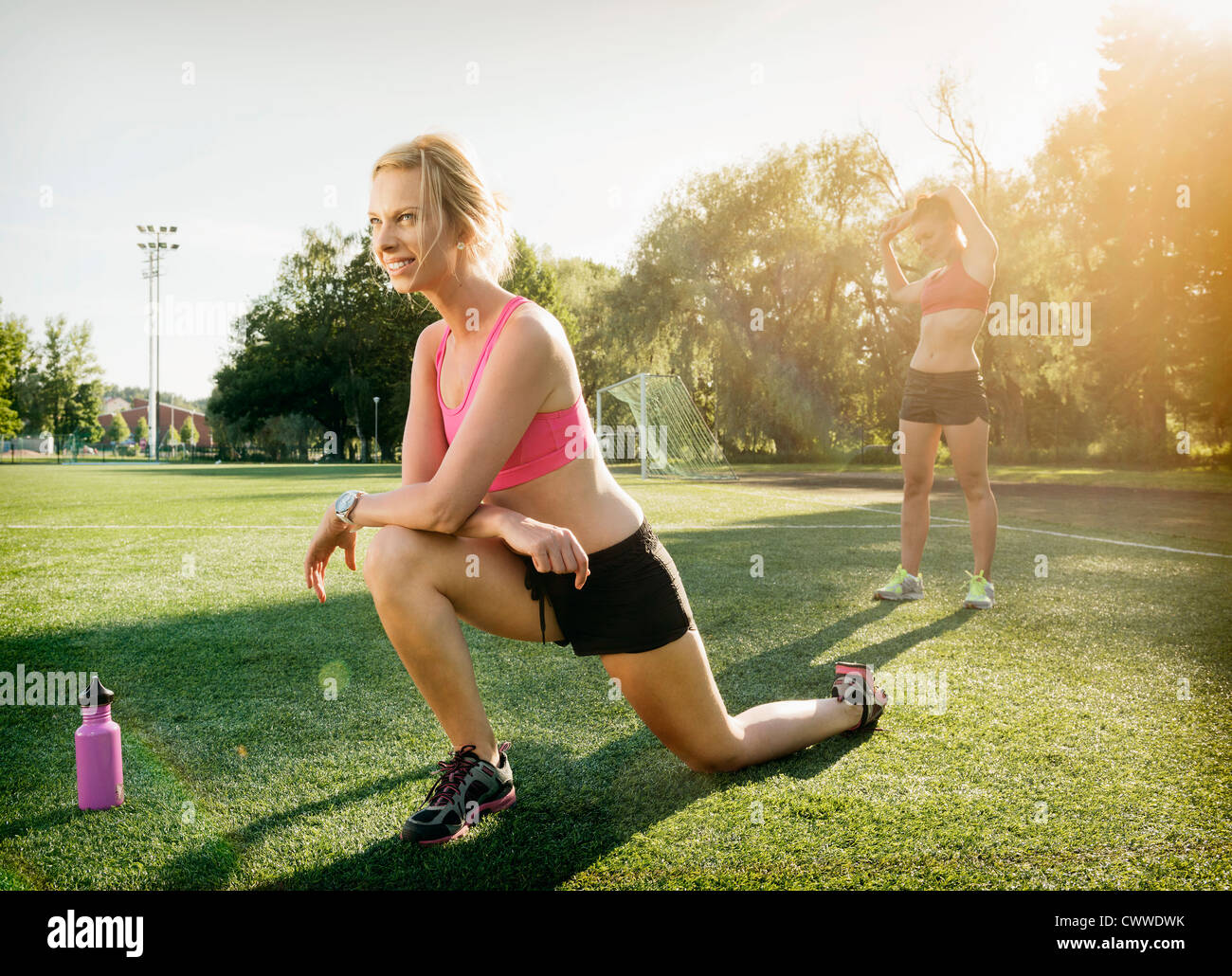 Runners stretching on grass in park Stock Photo