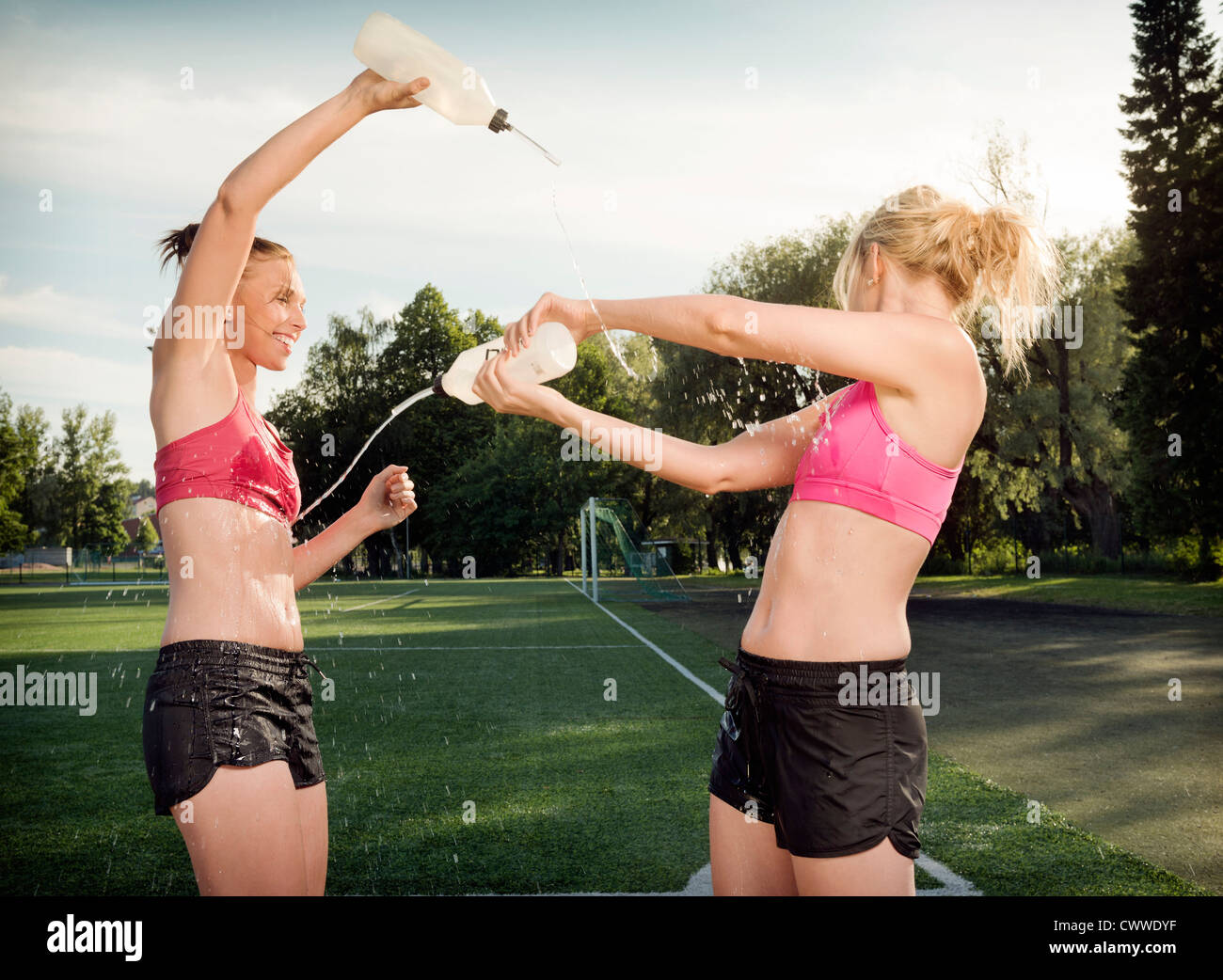 Runners splashing each other in park Stock Photo