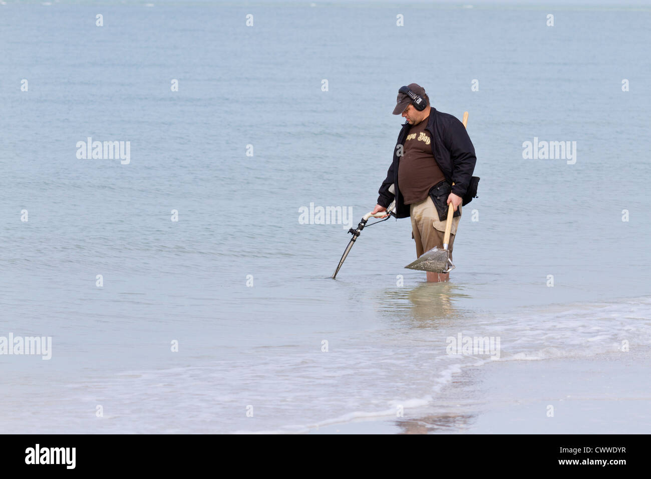 Man operating underwater metal detector along beach in Fort De Soto County Park in Tierra Verde, Florida Stock Photo
