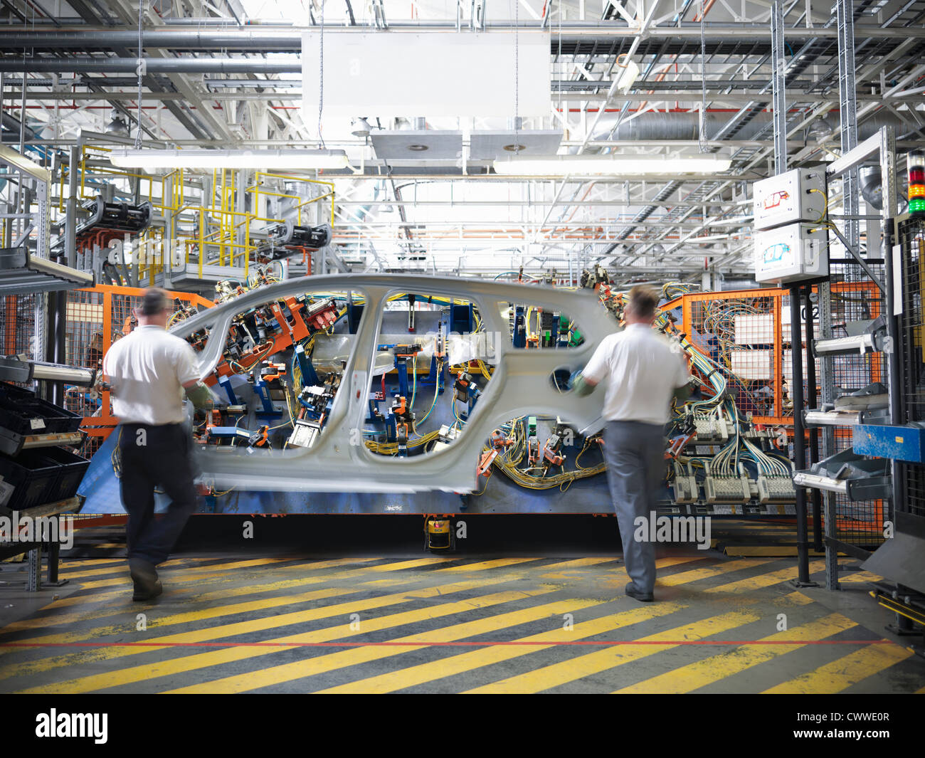 Workers with car body part in welding jig in car factory Stock Photo