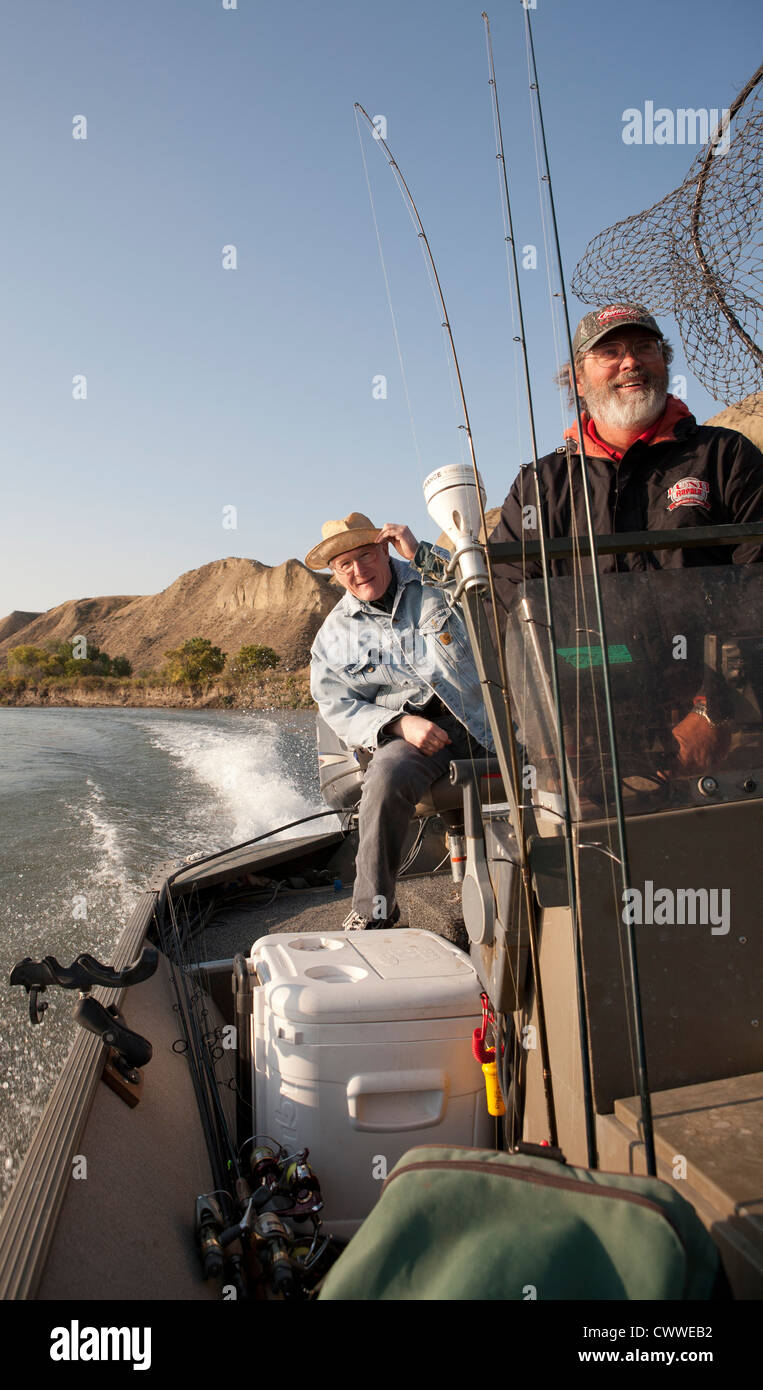 Guide, intent on walleye fishing, pilots his jet boat up the Missouri River as his client peers over his shoulder. Stock Photo