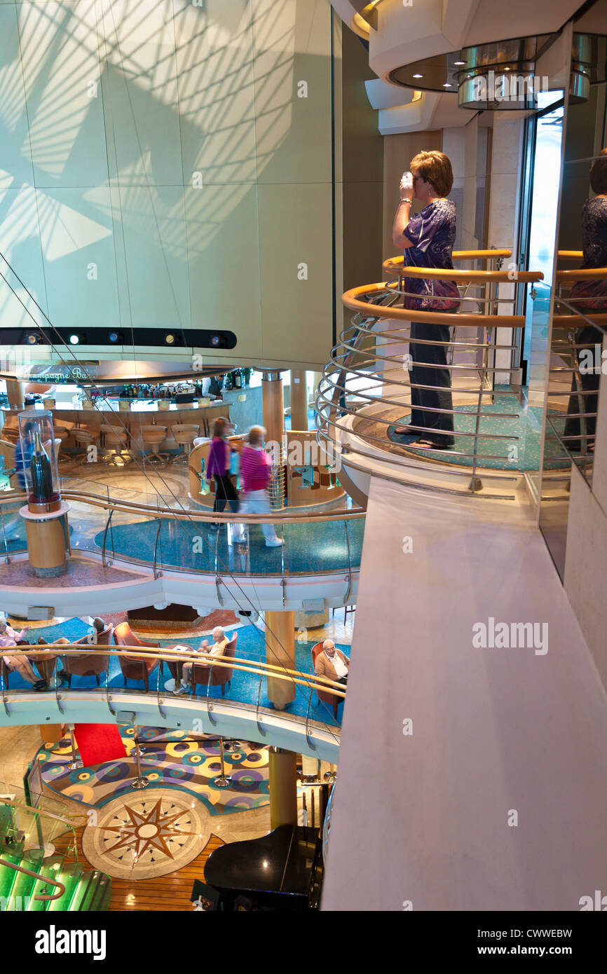Woman taking photo overlooking multi-level atrium inside Royal Caribbean's Radiance of the Seas cruise ship Stock Photo