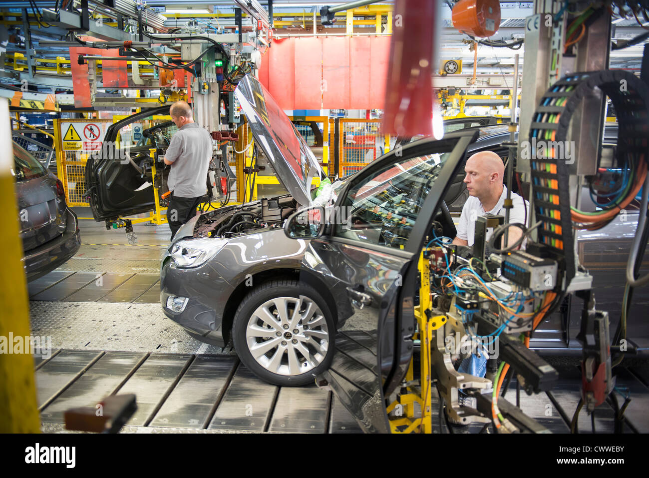 Car assembly workers fitting doors to cars on production ...