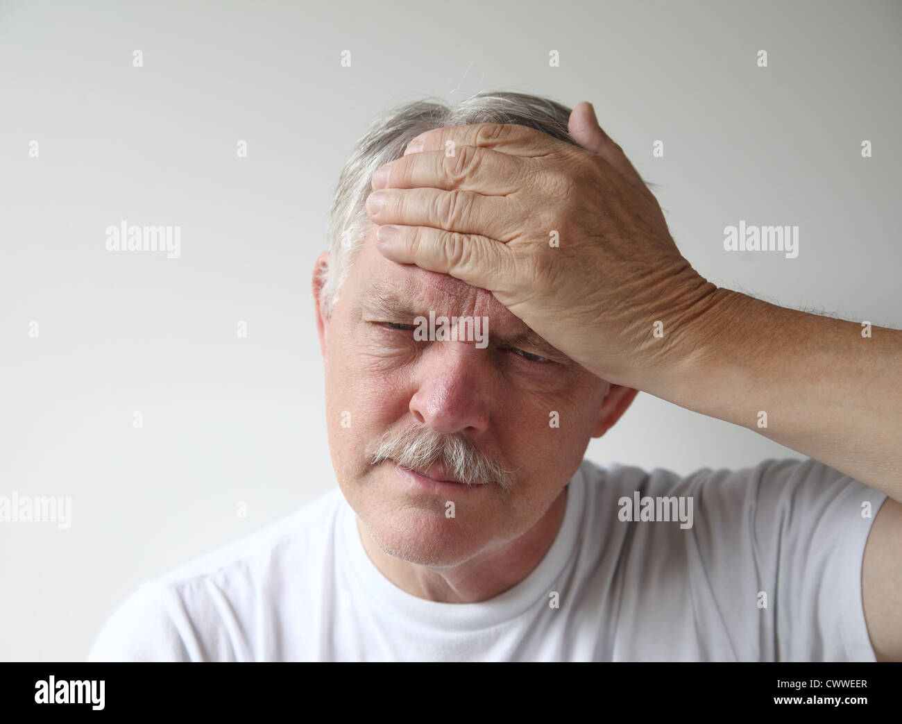 a man puts his hand to his forehead in pain Stock Photo