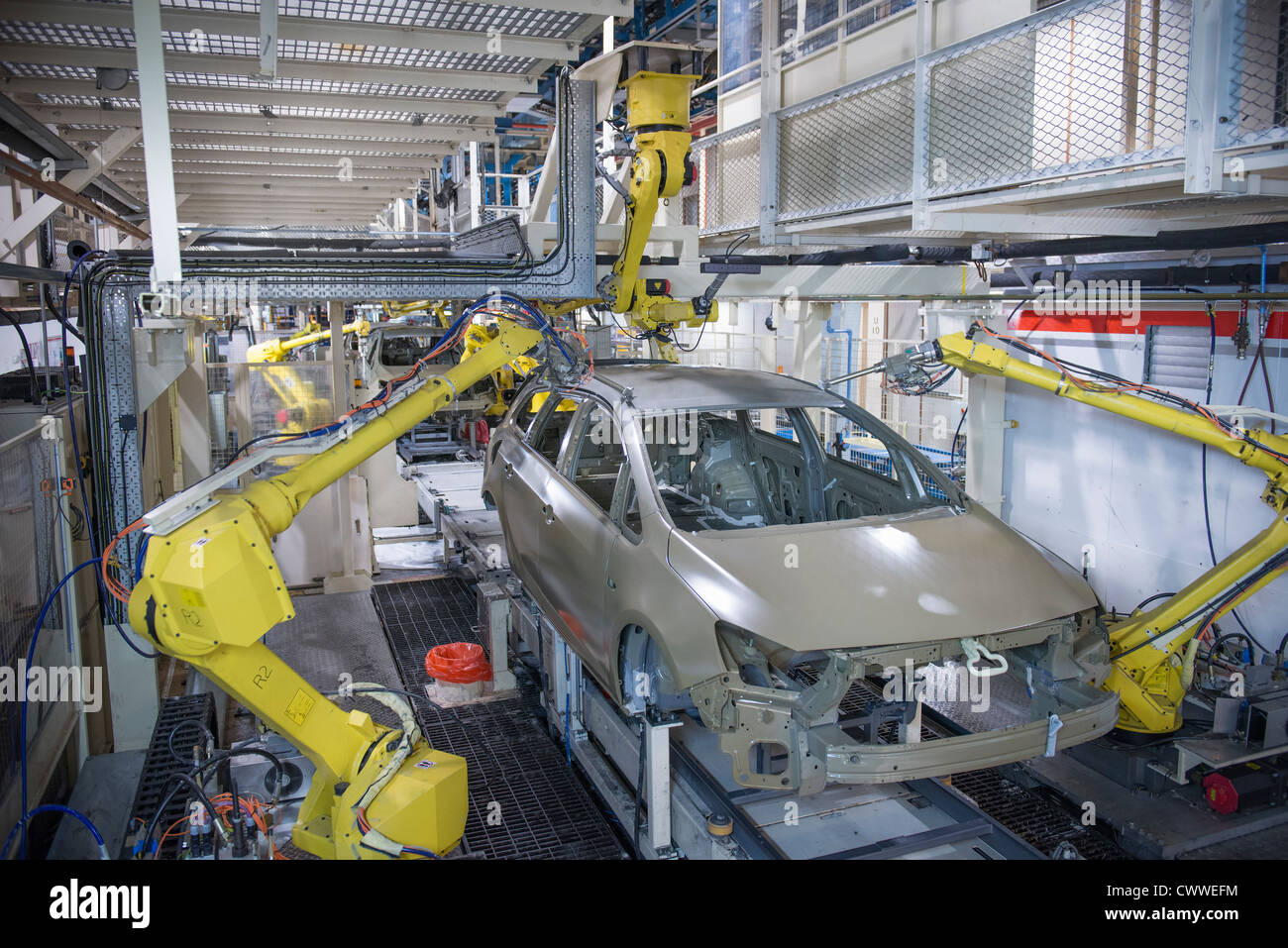 Robots applying sealant to cars in car factory Stock Photo