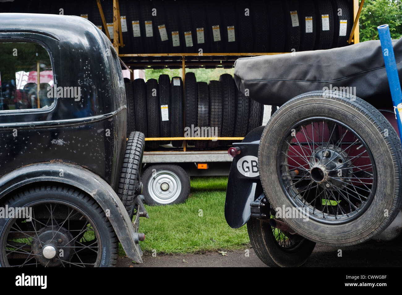 An Austin Seven and another vintage car parked by racks of tyres in the ...