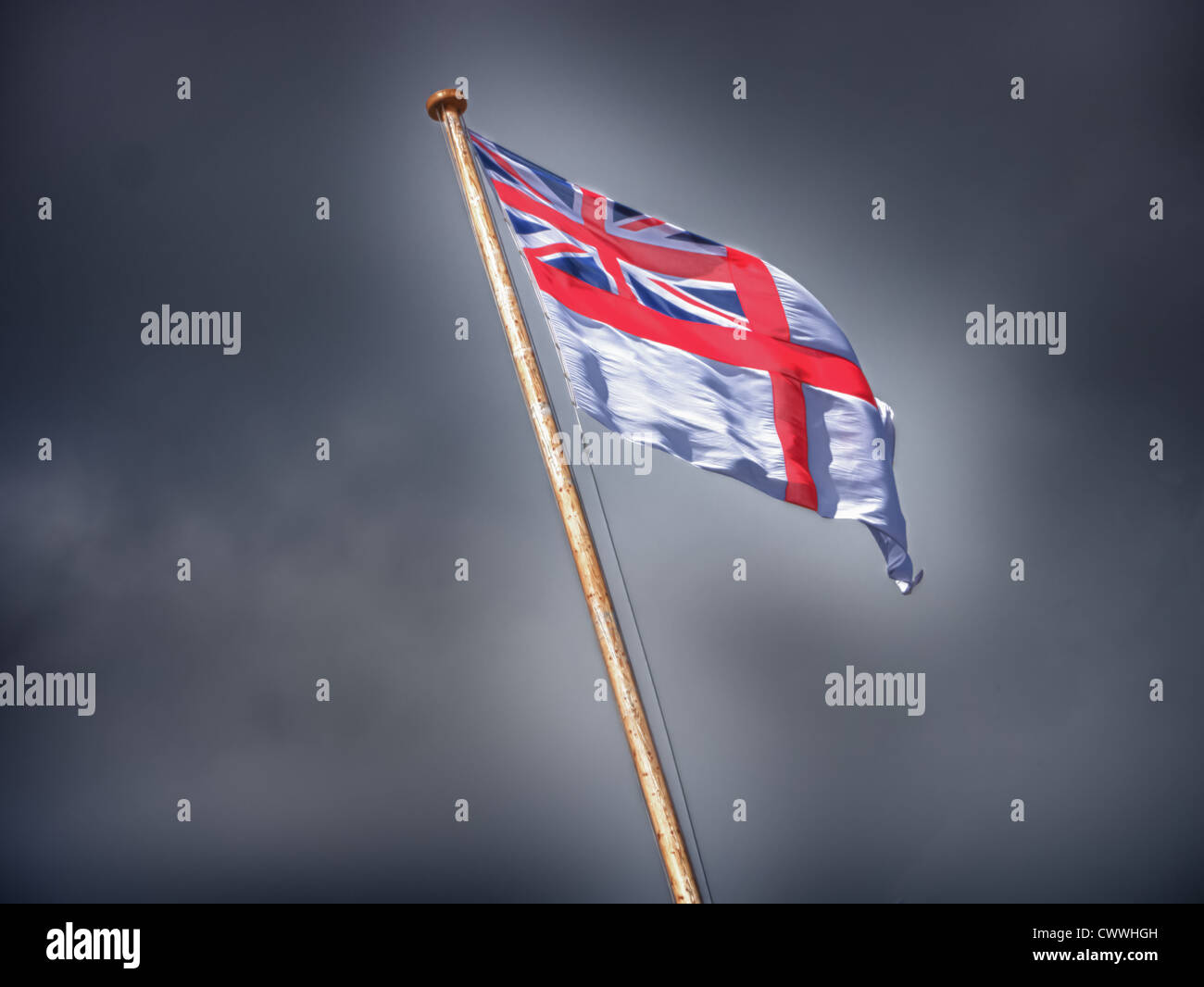 A White Ensign of the Royal Navy flies against storm clouds Stock Photo