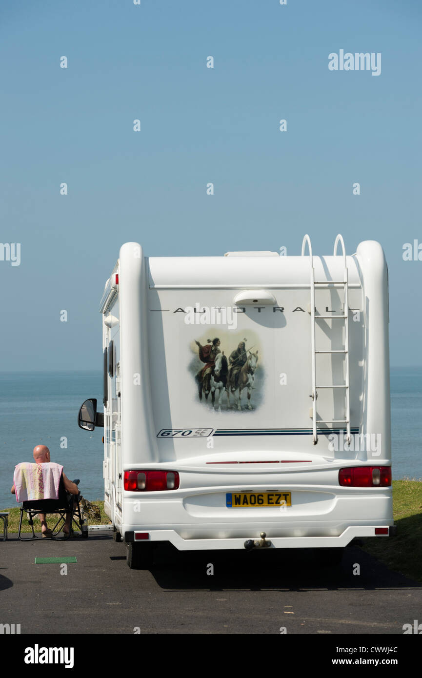 Summer: Rear view of a man sitting next to his campervan on a August ...