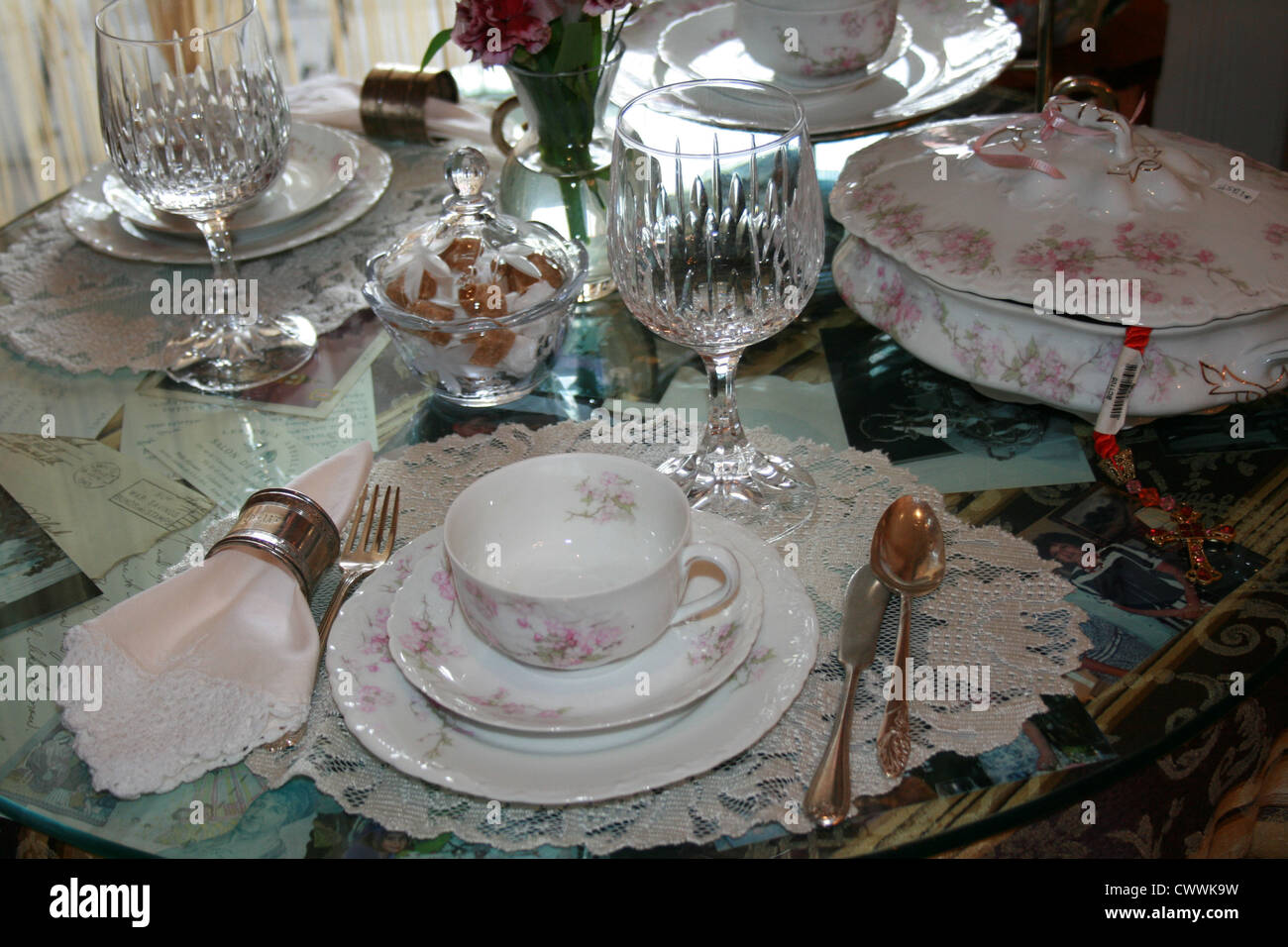 still life photo old vintage antique china dining room porcelain dinnerware set with lace and crystal wine glasses silverware Stock Photo