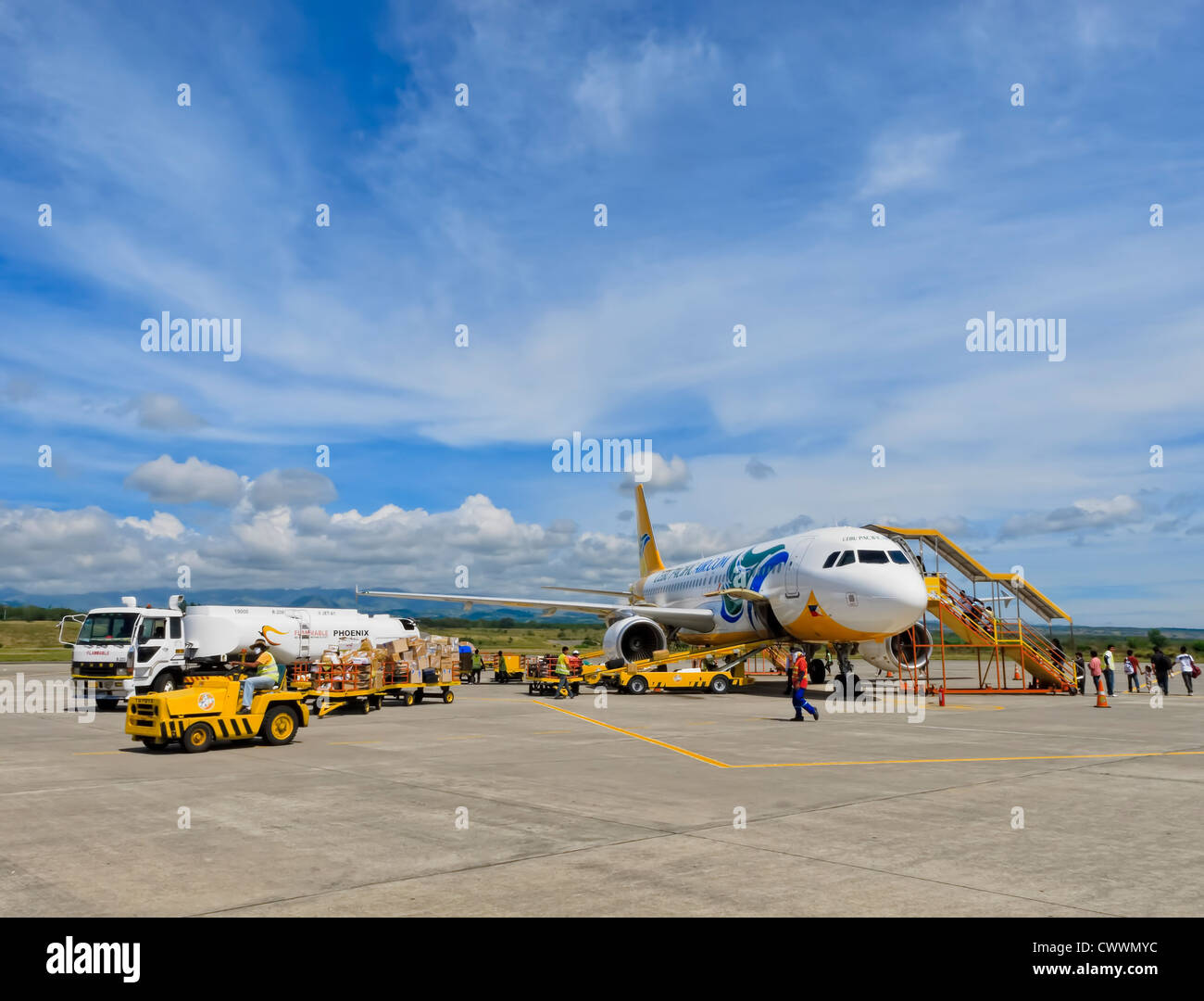 Gensan, Philippines - April 2, 2011: Passengers board a Cebu Pacific airplane bound for Manila, while airport ground personnel p Stock Photo