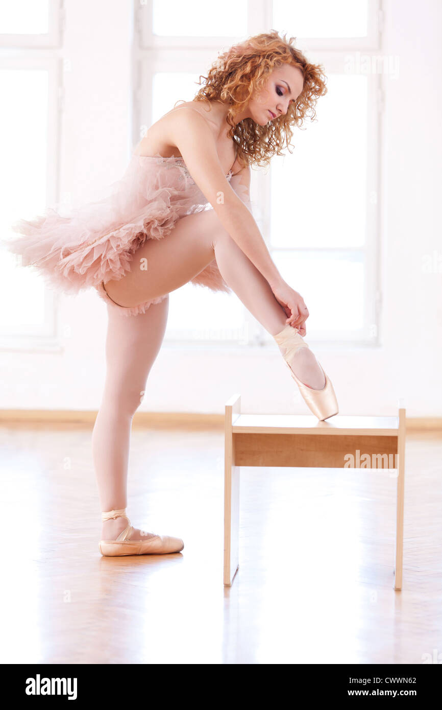 Young, blond ballerina tying her pointe. Stock Photo
