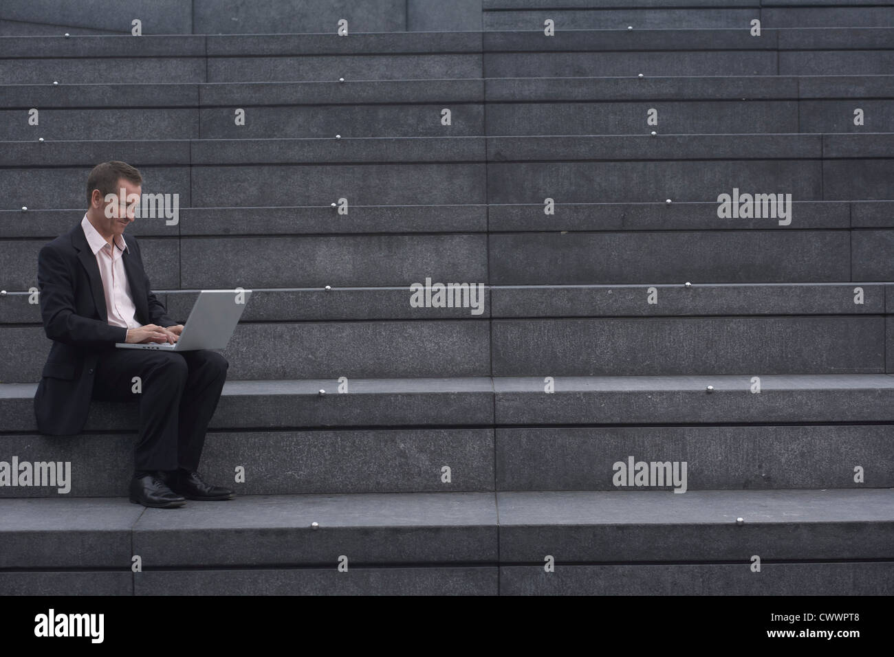 Businessman reading newspaper on steps Stock Photo