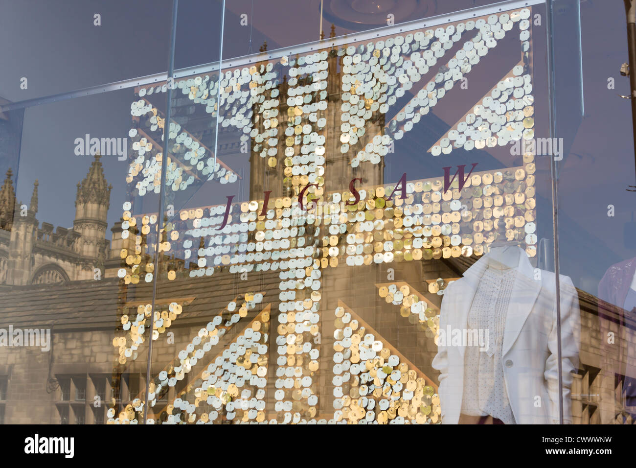 Manchester cathedral reflected in the window of Jigsaw, the fashion and homeware shop in the Triangle Shopping Centre. Stock Photo