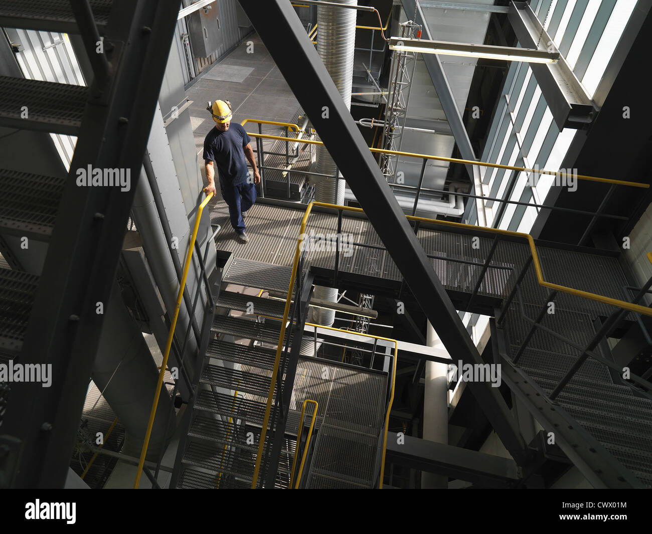Worker climbing staircase in factory Stock Photo