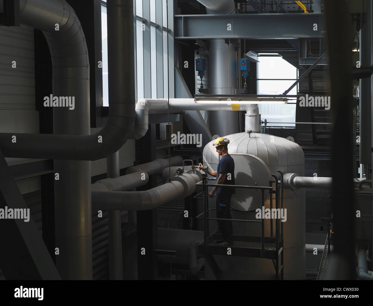 Worker operating machinery in factory Stock Photo