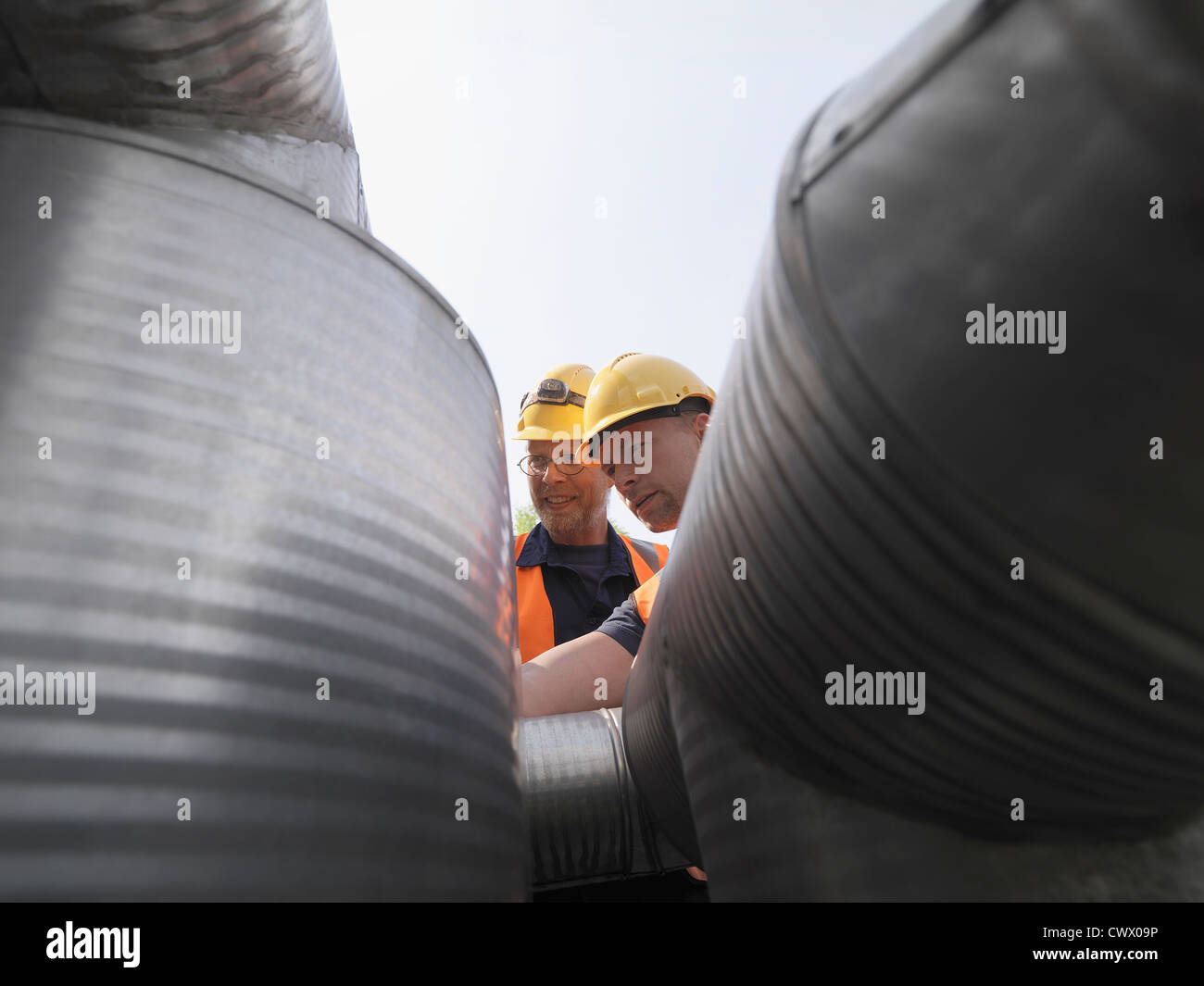 Workers examining machinery on site Stock Photo