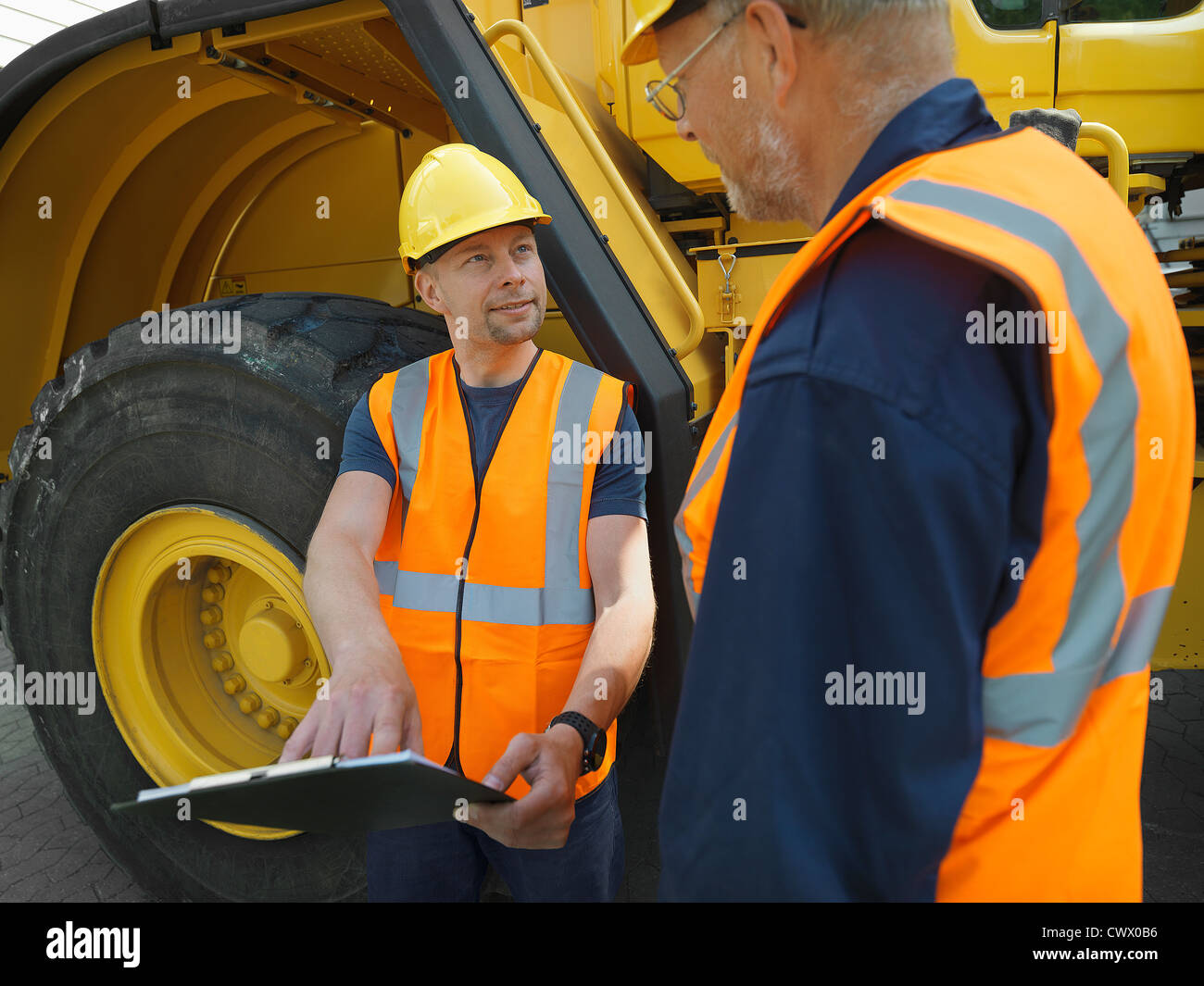 Workers reading clipboard on site Stock Photo