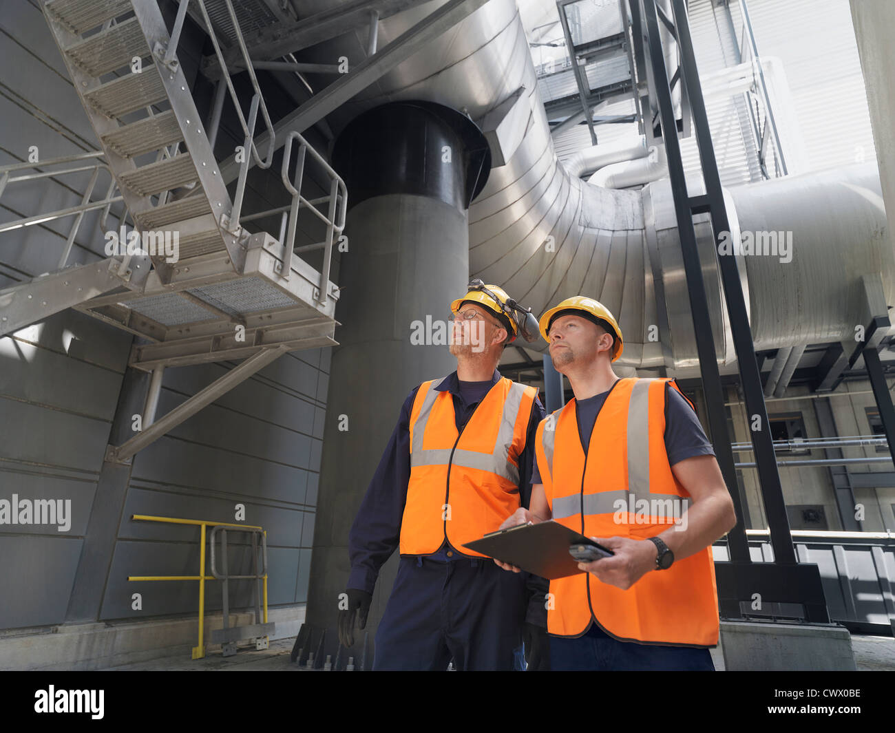 Workers examining machinery in factory Stock Photo