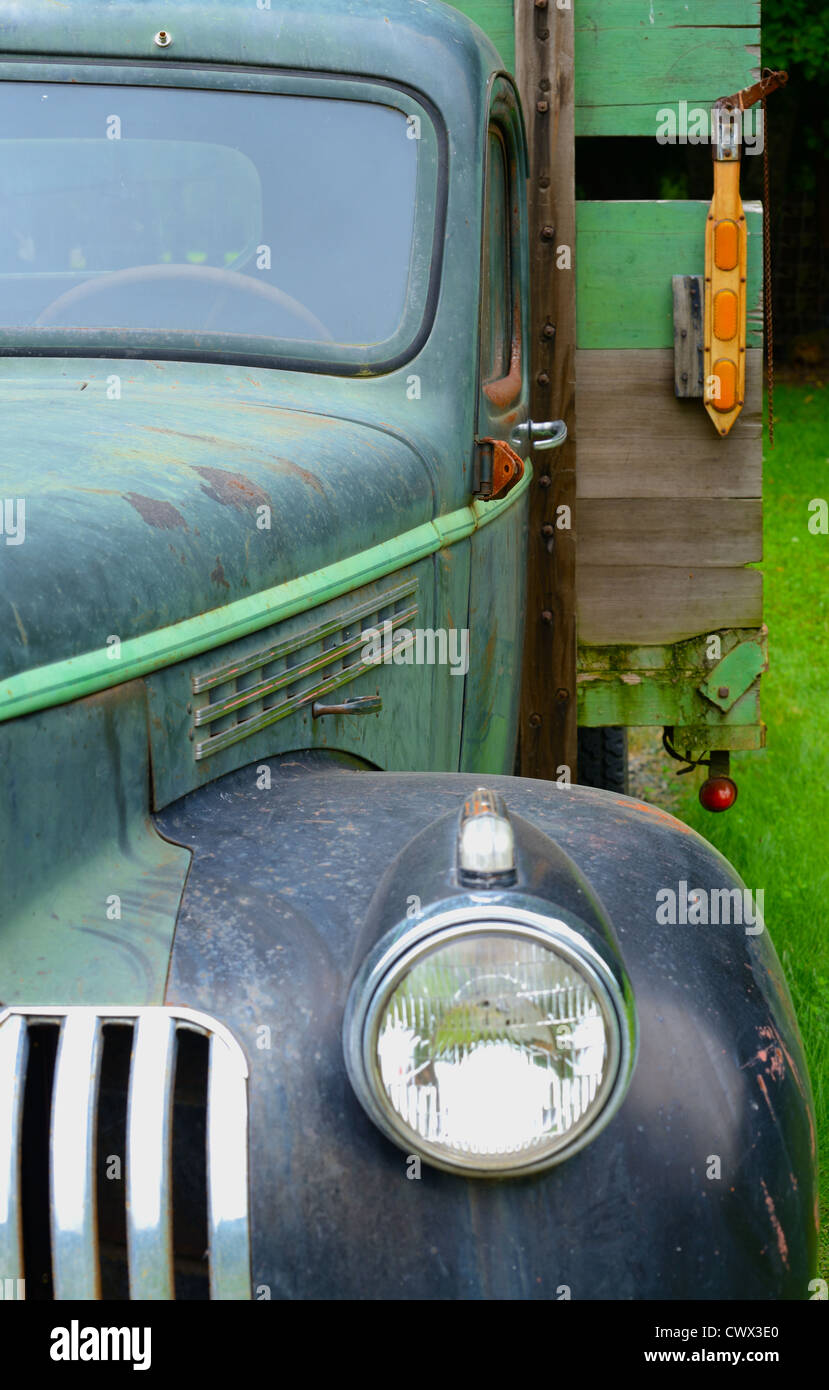 Photo of the left side of an old antique faded color truck showing steering wheel and the back bed of the truck Stock Photo