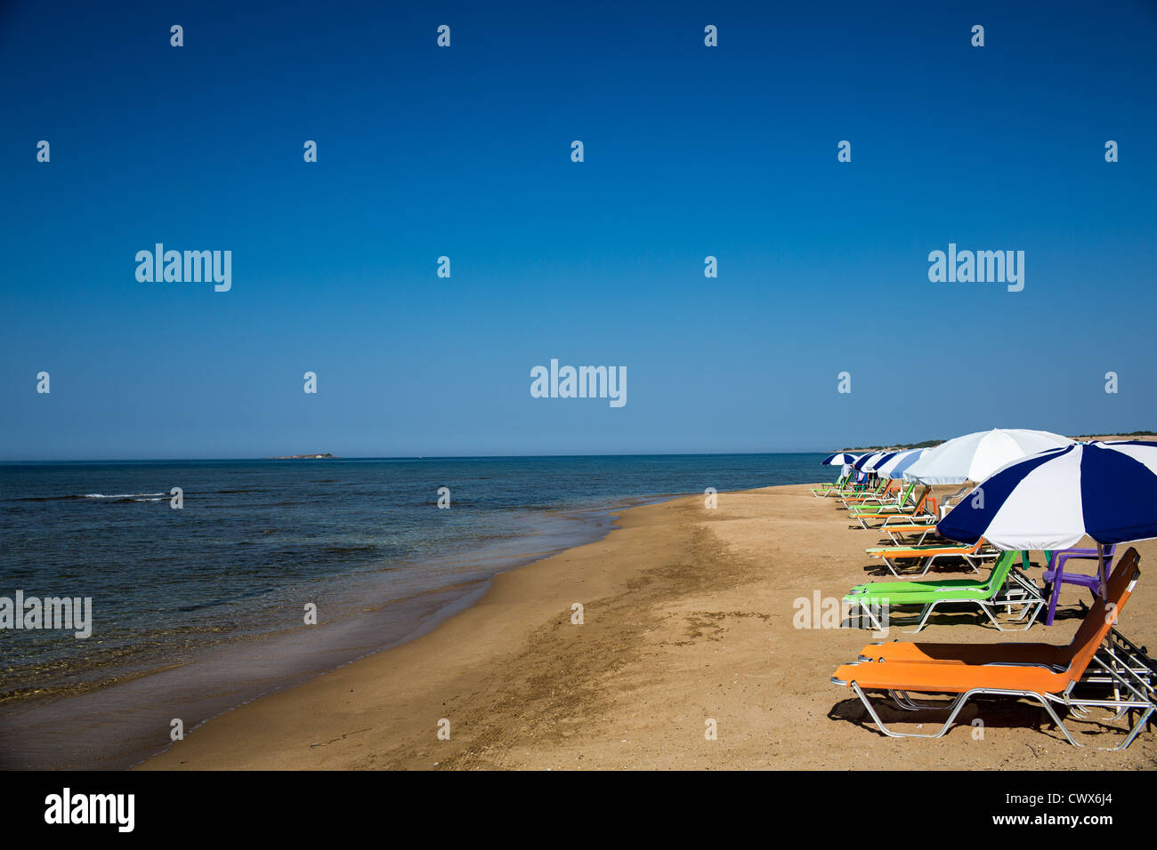 A row of empty coloured sunbeds on the beach of Agios Georgios, Corfu, Ionian Islands, Greece. Stock Photo