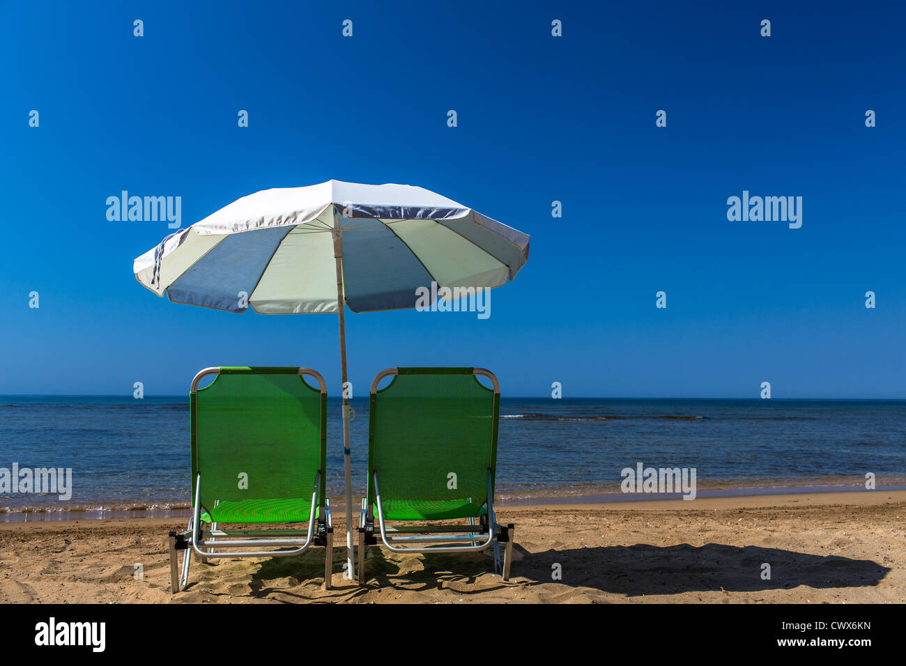 Beach sunbeds with an umbrella on the beach of Agios Georgios, Corfu, Ionian Islands, Greece. Stock Photo