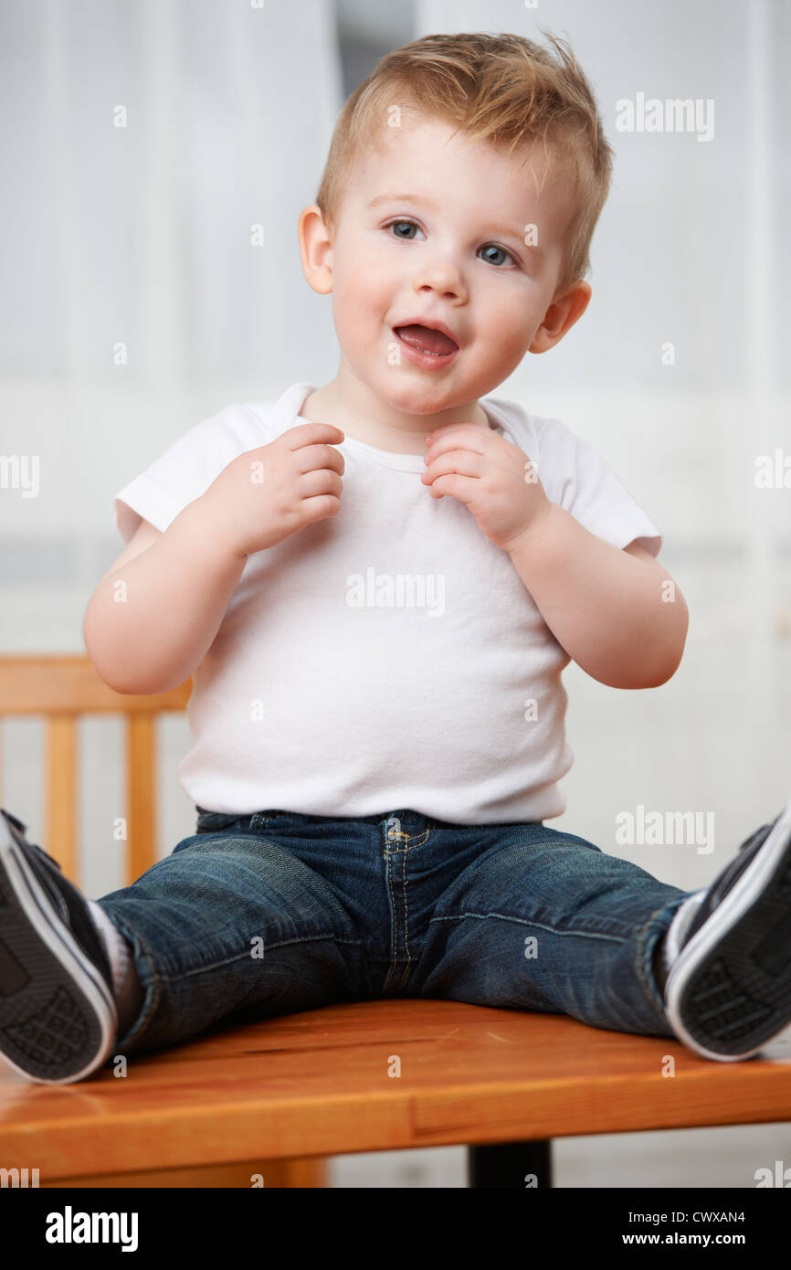 Cute baby boy at 18 months wearing jeans and t-shirt sitting on ...
