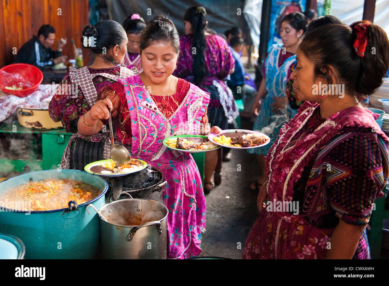 Mayan women girls serving meal at food stand in local market, Chichicastenango, Guatemala. Stock Photo