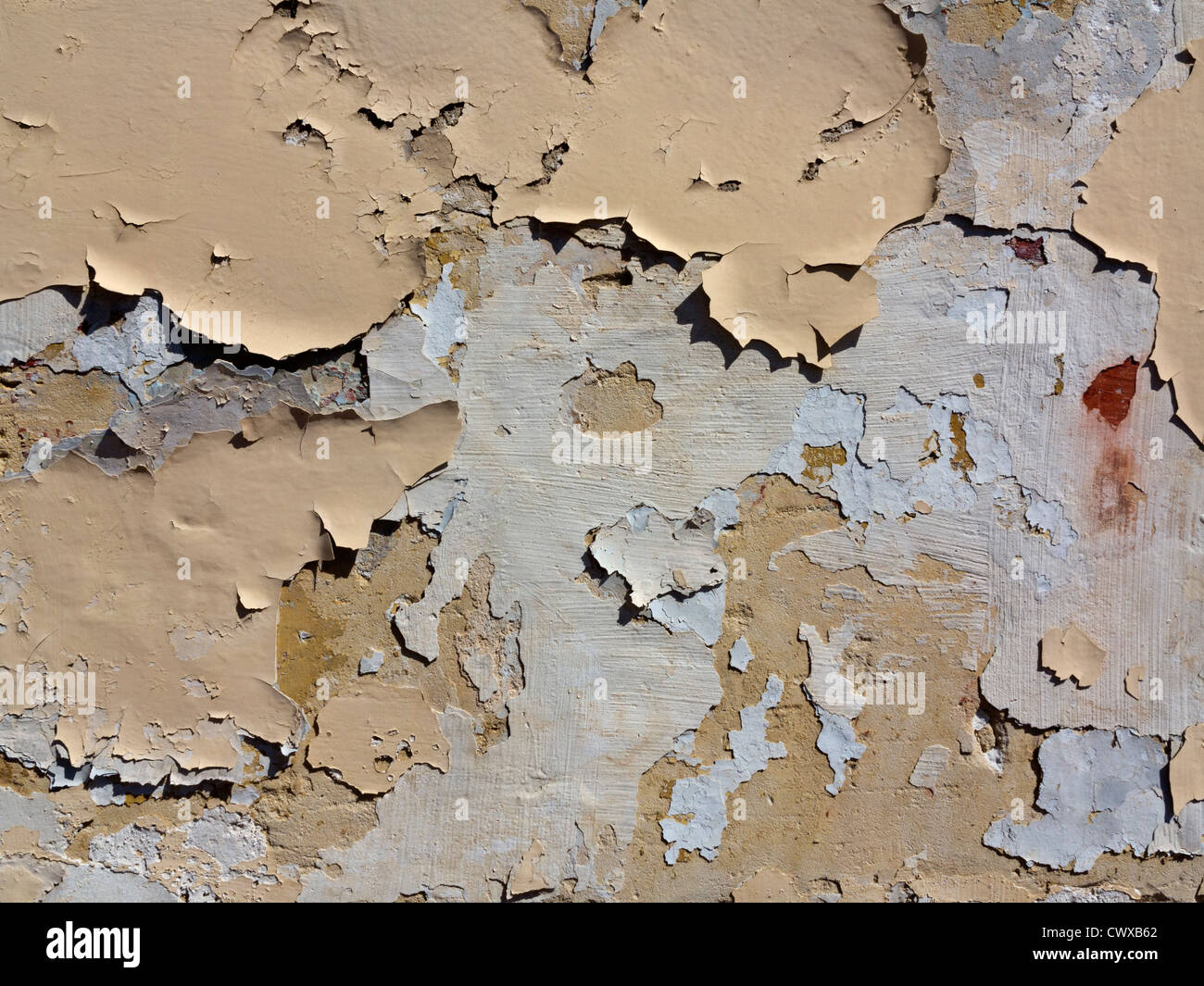 Close up of flaking paint layers and plaster on vertical wall surface Stock Photo