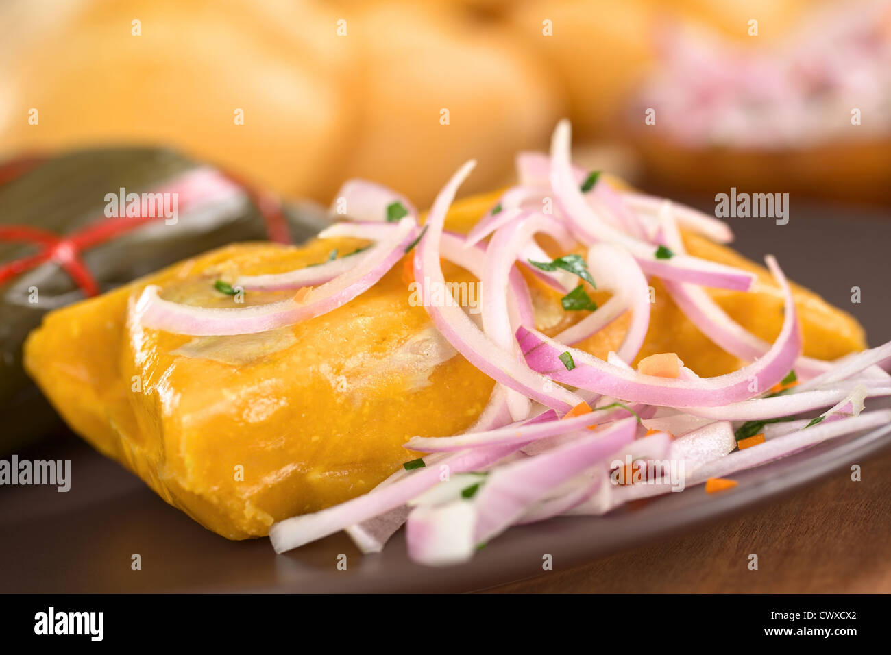 Peruvian tamale (traditionally eaten for breakfast on Sundays) made of corn and chicken and served with salsa criolla Stock Photo