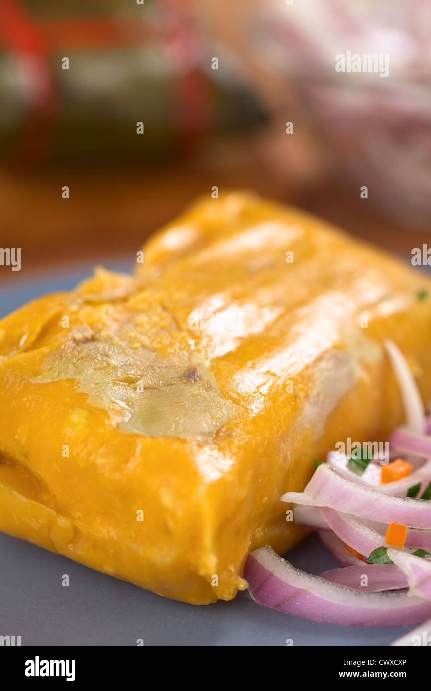 Peruvian tamale (traditionally eaten for breakfast on Sundays) made of corn and chicken and served with salsa criolla Stock Photo