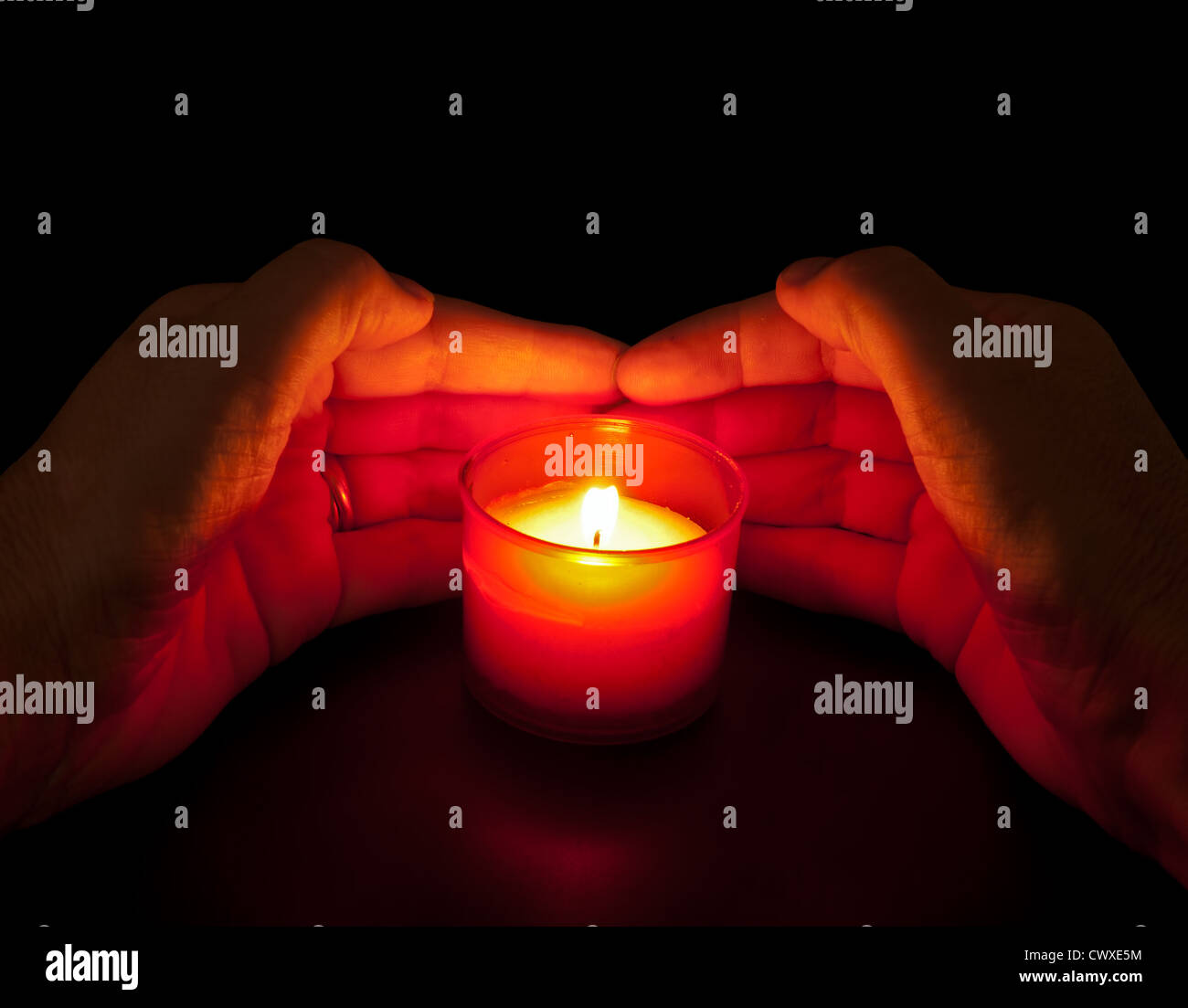 In memoriam - hands with votive candle in red holder Stock Photo