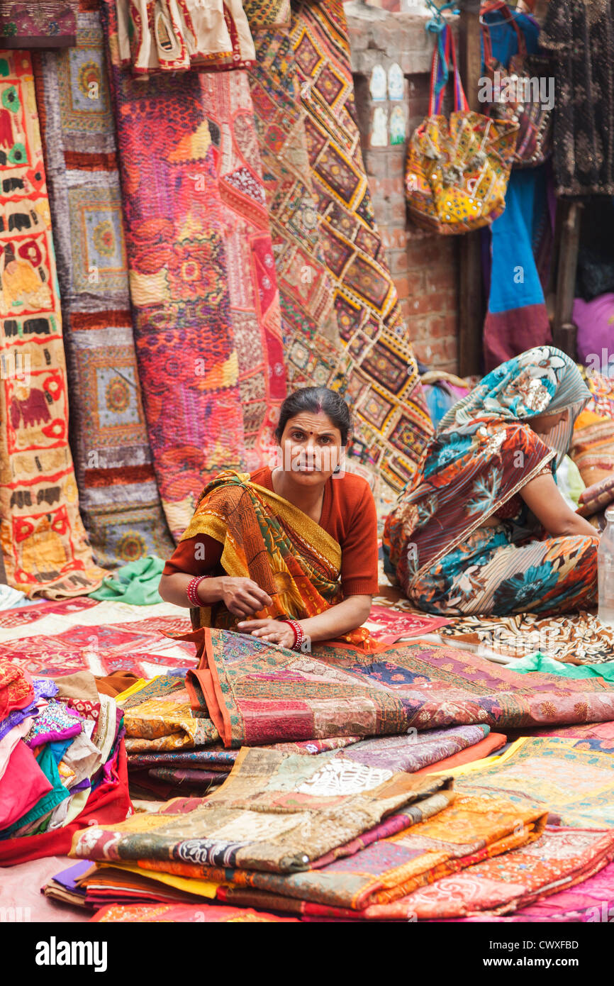 New Delhi roadside street market, sellers selling colourful carpets, rugs, cloth and clothes, woman wearing traditional sari Stock Photo