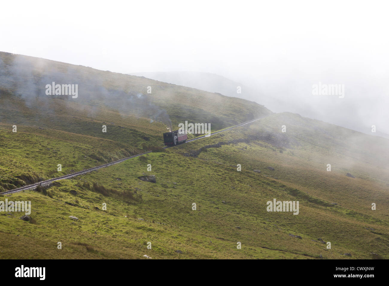 An engine and carriage make their way up the Snowdon Mountain Railway track Stock Photo