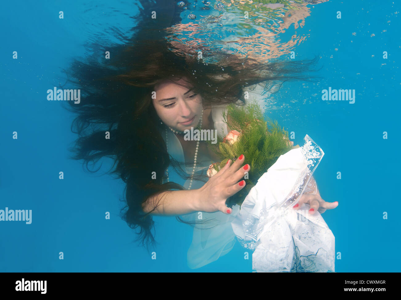 A young woman with big hair posing in a pool underwater Stock Photo