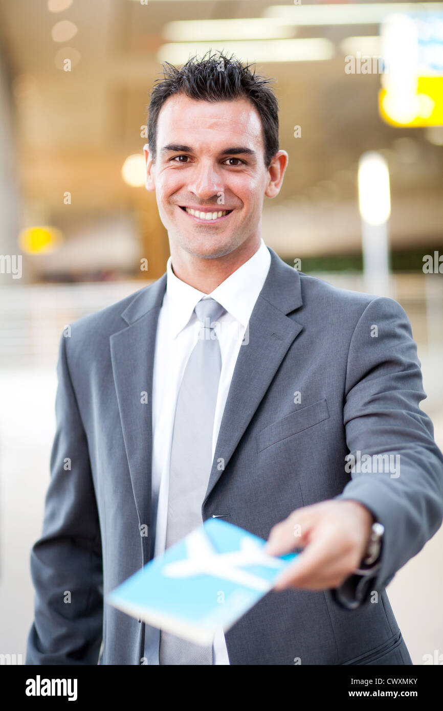 smiling handsome businessman handing over air ticket at airport check in counter Stock Photo