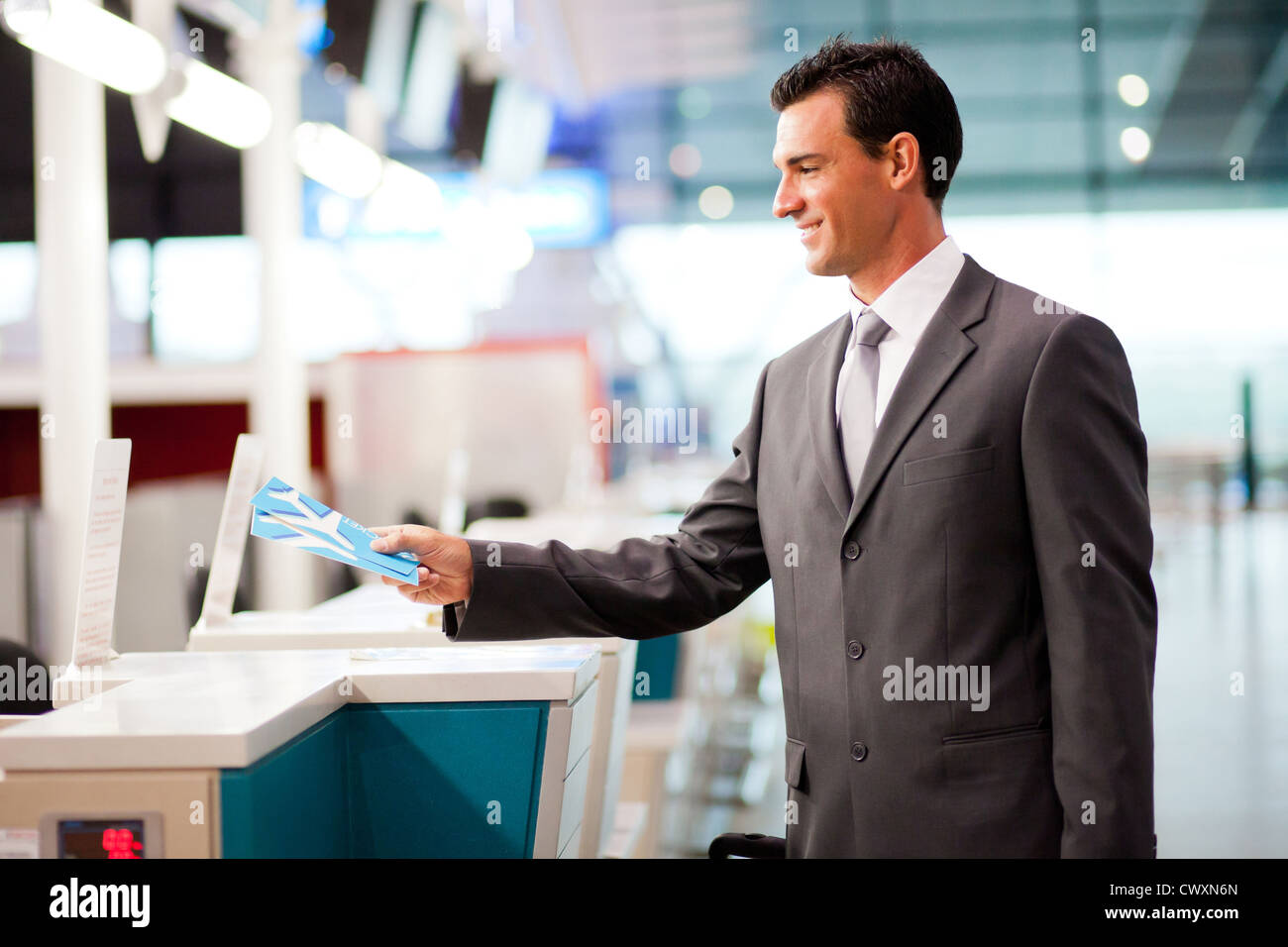 handsome businessman handing over air ticket at airline check in counter Stock Photo