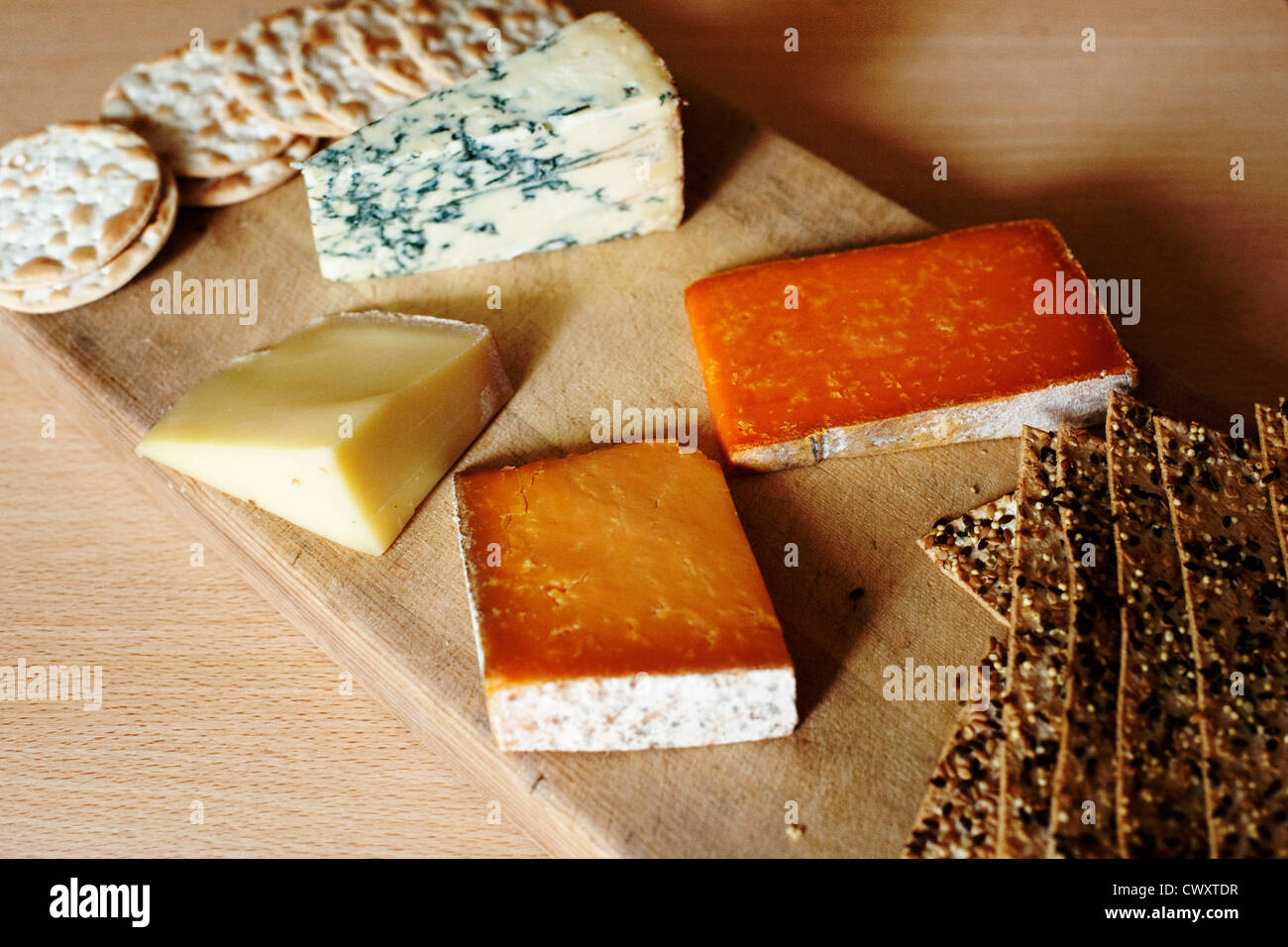 A selection of English cheeses with crackers on a cheese board. Stock Photo