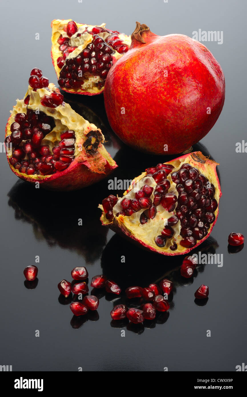 Red bright pomegranate on a black background. Stock Photo