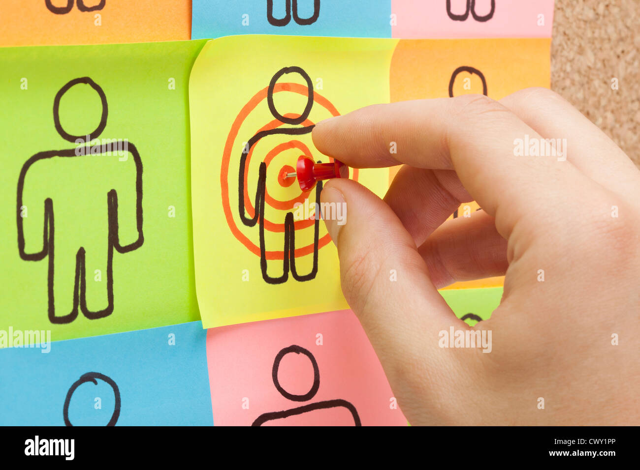 Hand pinning a sticky note in the center of a customer target on cork board Stock Photo