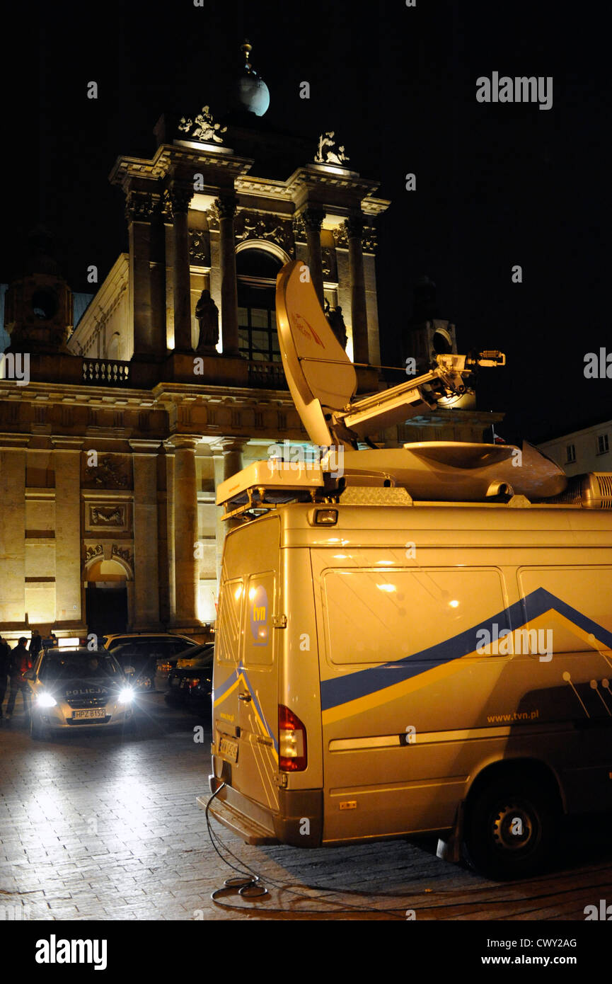 A van of a television company assisted by a police car during a live transmission in front of a church. Stock Photo