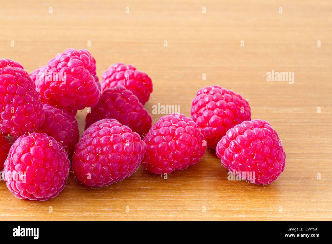 Heap of red ripe raspberries on wooden table Stock Photo
