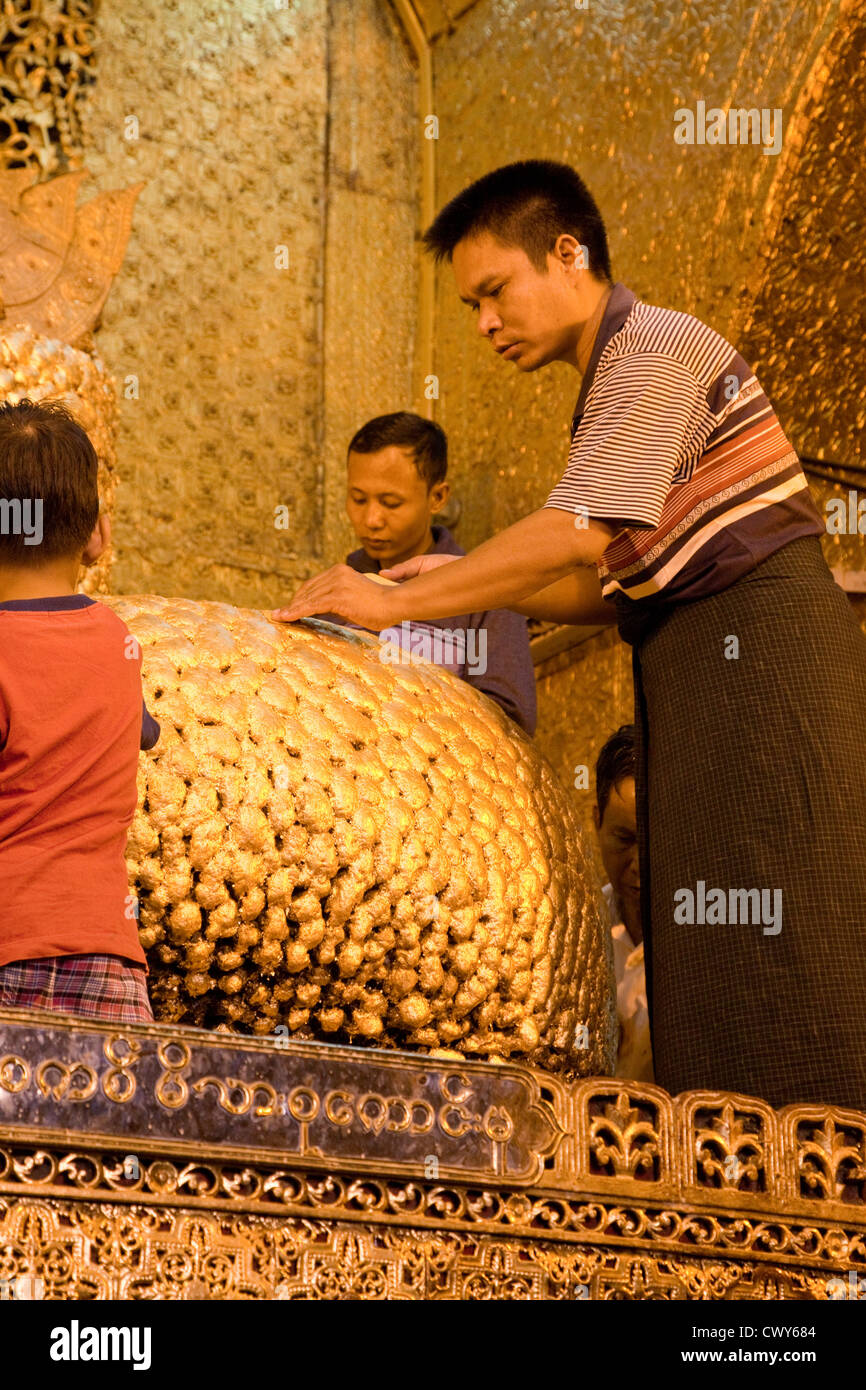 Myanmar, Burma. Mandalay. Mahamuni Buddhist Temple. Men apply gold leaf